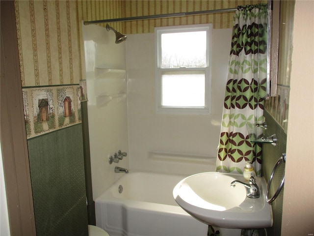 bathroom featuring wallpapered walls, shower / bath combo, and a sink