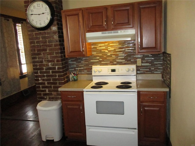 kitchen featuring white electric range oven, wood finished floors, light countertops, under cabinet range hood, and tasteful backsplash