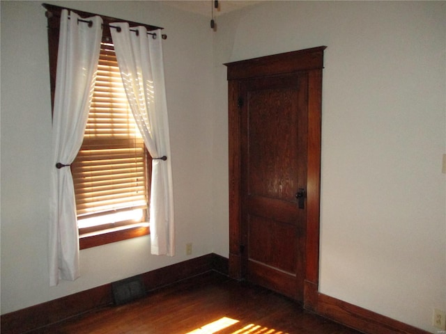 spare room featuring visible vents, baseboards, and wood finished floors