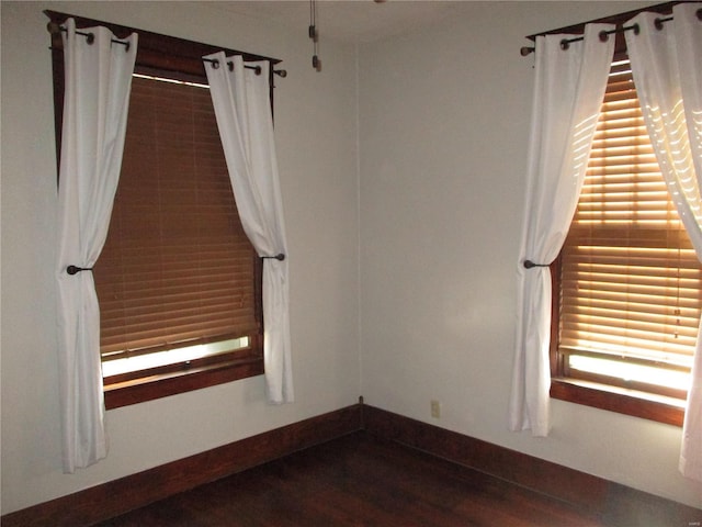 spare room featuring baseboards and wood finished floors