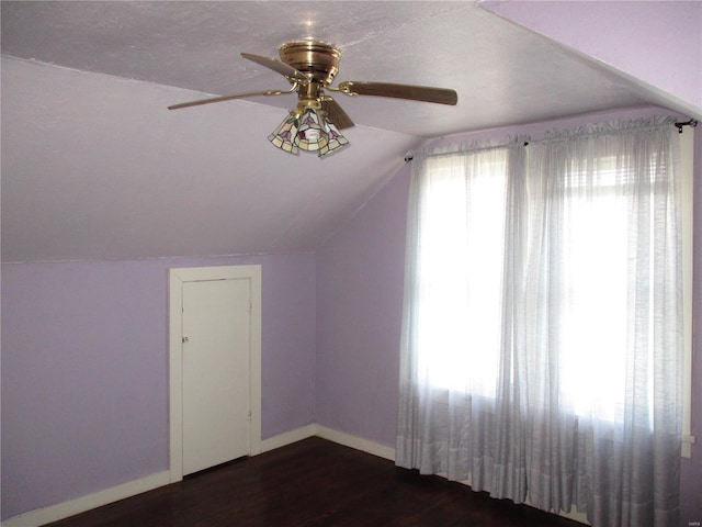 additional living space featuring baseboards, lofted ceiling, ceiling fan, and dark wood-style flooring