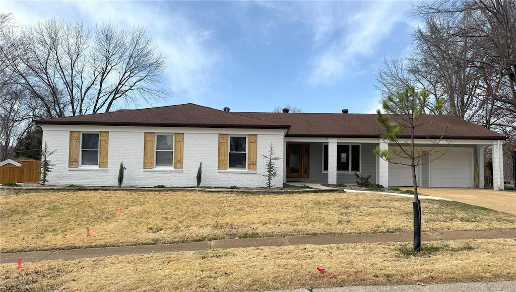 ranch-style home featuring a front yard, brick siding, a garage, and driveway