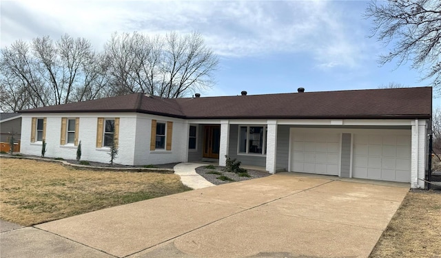 ranch-style house with a garage, brick siding, roof with shingles, and concrete driveway