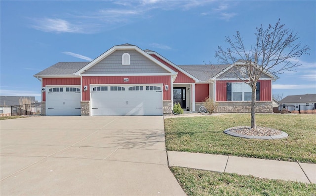 view of front of home featuring a front yard, fence, concrete driveway, a garage, and stone siding