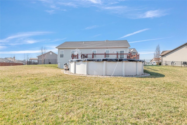 rear view of house featuring a fenced in pool, a lawn, and fence