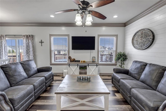 living area featuring baseboards, wood finished floors, ornamental molding, and a ceiling fan