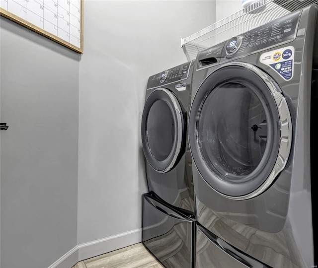 laundry room with baseboards, light wood-style floors, laundry area, and washing machine and clothes dryer