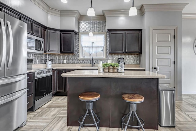 kitchen featuring tasteful backsplash, a kitchen island, a breakfast bar, appliances with stainless steel finishes, and a sink