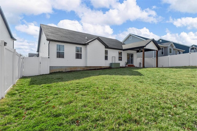 rear view of house featuring a lawn, cooling unit, and a fenced backyard