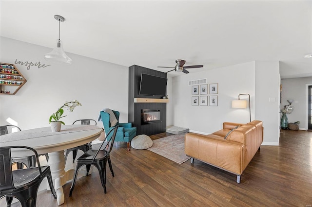 living room with wood finished floors, a fireplace, baseboards, and ceiling fan