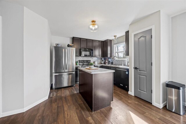 kitchen with dark wood finished floors, decorative backsplash, dark brown cabinets, appliances with stainless steel finishes, and a center island