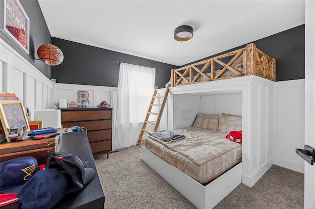 bedroom with carpet flooring, a decorative wall, and a wainscoted wall