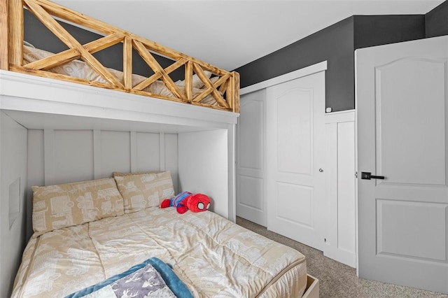 carpeted bedroom with a decorative wall and a closet