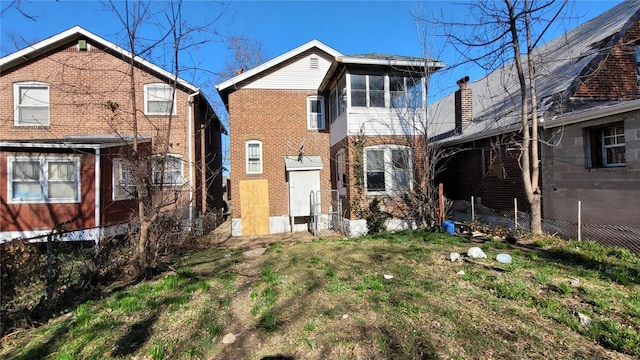 back of house with brick siding and a lawn