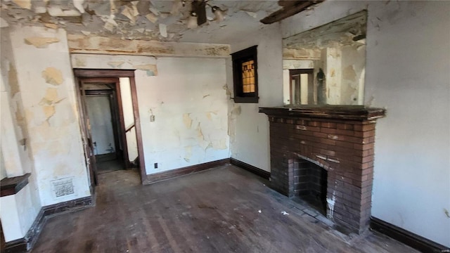 unfurnished living room with a brick fireplace, baseboards, and wood finished floors