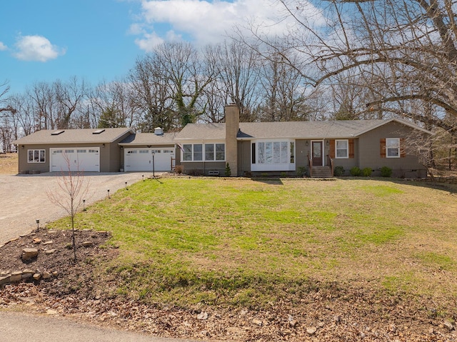 ranch-style house featuring a chimney, driveway, an attached garage, and a front lawn