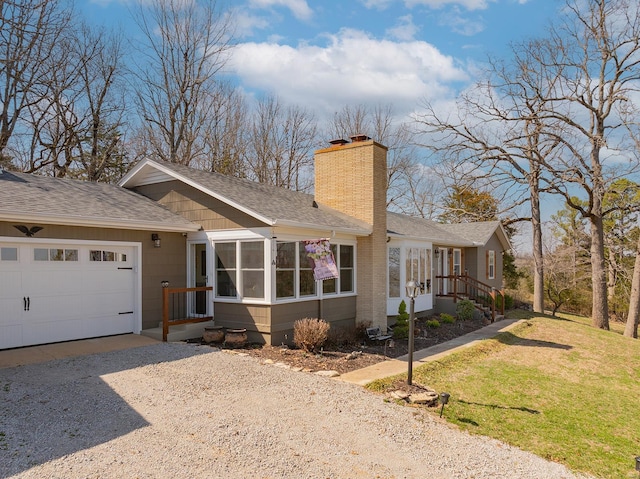 ranch-style home with driveway, a shingled roof, a front yard, an attached garage, and a chimney