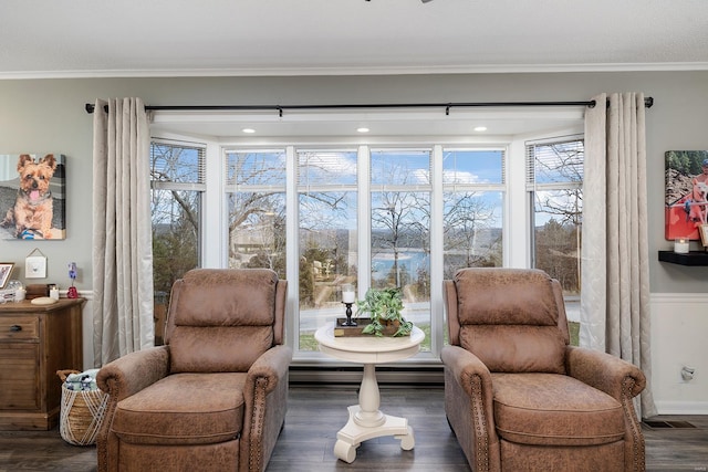 living area with dark wood finished floors, baseboard heating, and ornamental molding