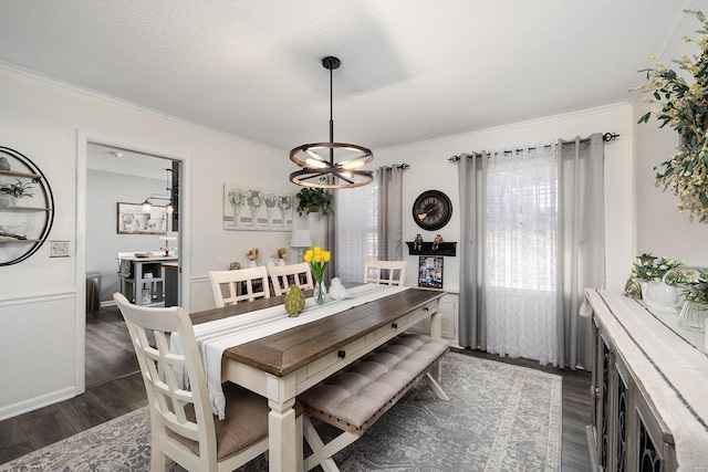 dining space featuring a notable chandelier, ornamental molding, dark wood-style flooring, and a textured ceiling