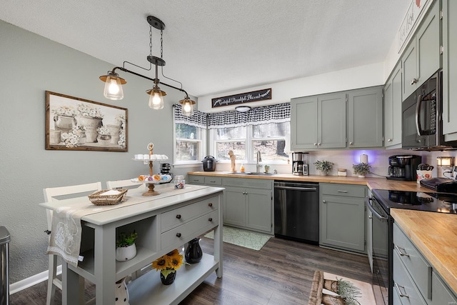 kitchen featuring wooden counters, gray cabinetry, a sink, black appliances, and dark wood-type flooring