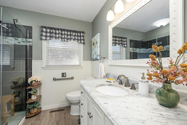 bathroom featuring visible vents, a stall shower, wood finished floors, wainscoting, and vanity