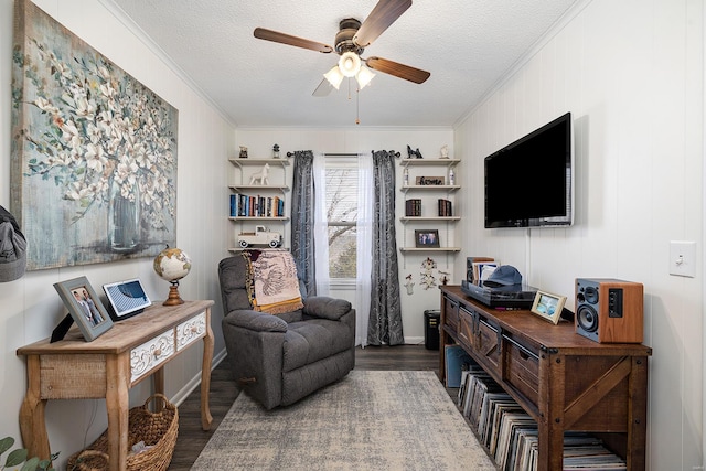 living area featuring a textured ceiling, crown molding, wood finished floors, and ceiling fan