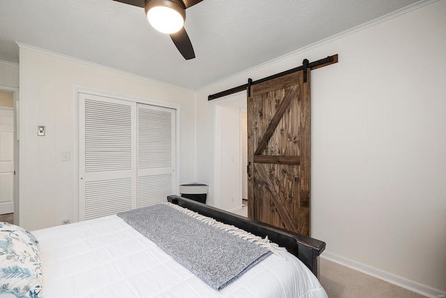 carpeted bedroom with crown molding, baseboards, a barn door, a closet, and a textured ceiling