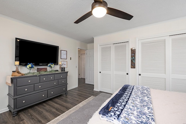 bedroom featuring dark wood-style floors, a textured ceiling, two closets, and crown molding