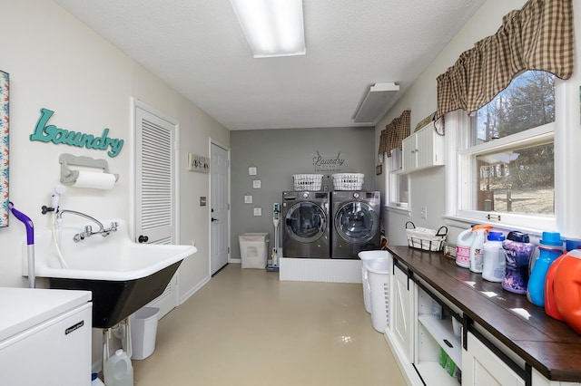 laundry area featuring a sink, a textured ceiling, washing machine and dryer, and laundry area