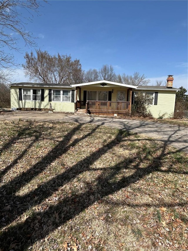 ranch-style home with a porch, driveway, and a chimney