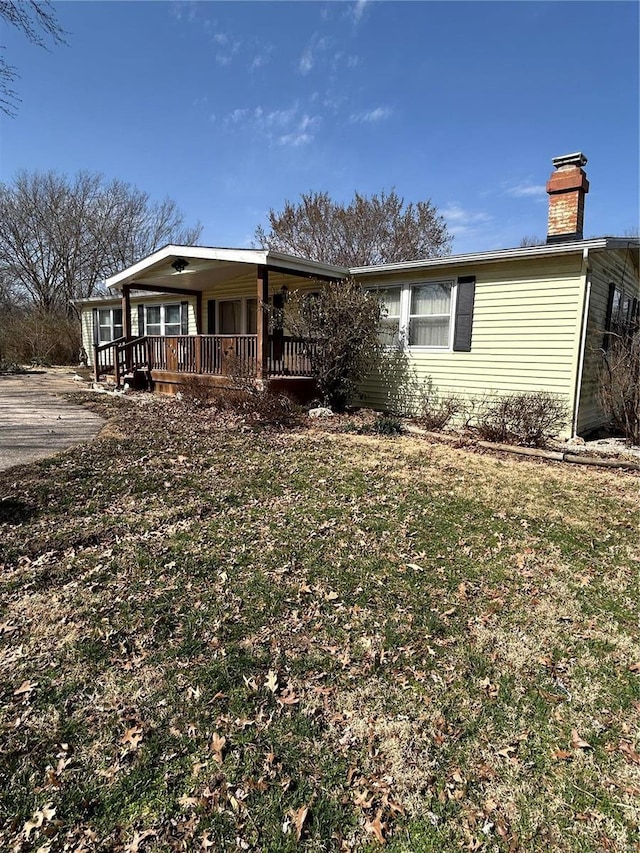 view of front of house featuring a front yard, covered porch, and a chimney