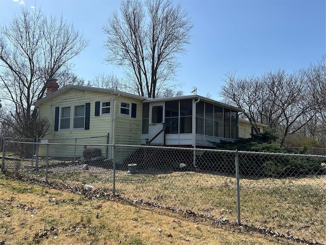 view of front of house featuring fence, a chimney, and a sunroom