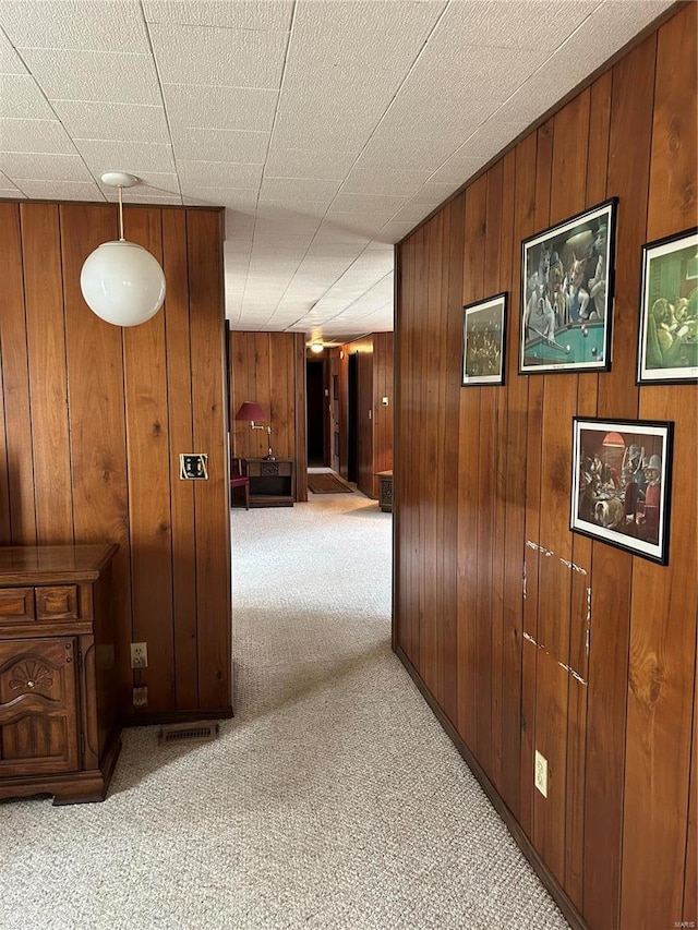 hall with wooden walls and carpet flooring