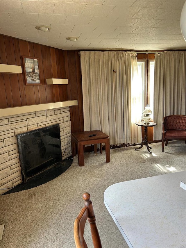 living room featuring wooden walls, a fireplace, and carpet floors