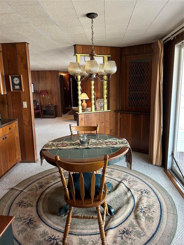 carpeted dining space with wooden walls