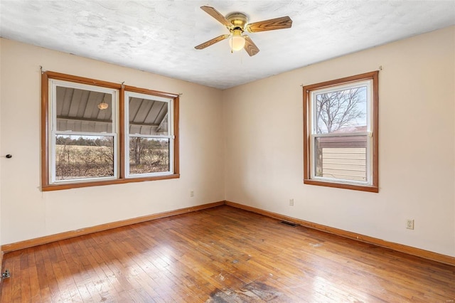 unfurnished room featuring baseboards, wood-type flooring, a textured ceiling, and ceiling fan