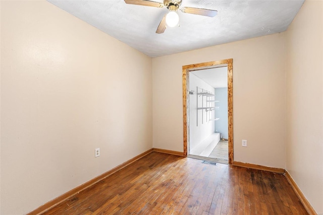 spare room with visible vents, wood-type flooring, baseboards, and ceiling fan