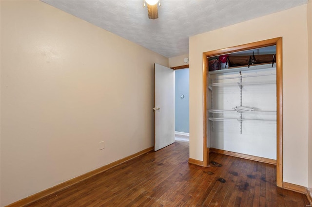 unfurnished bedroom with baseboards, wood-type flooring, a closet, and a ceiling fan