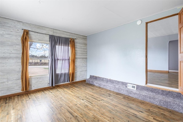 spare room with visible vents, arched walkways, and hardwood / wood-style floors