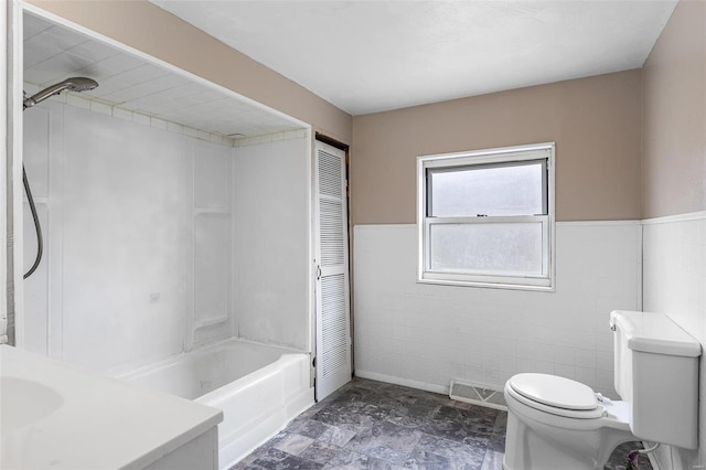 bathroom with washtub / shower combination, a wainscoted wall, visible vents, tile walls, and toilet