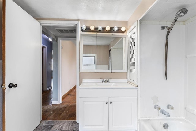 bathroom featuring vanity, shower / bathing tub combination, baseboards, and visible vents