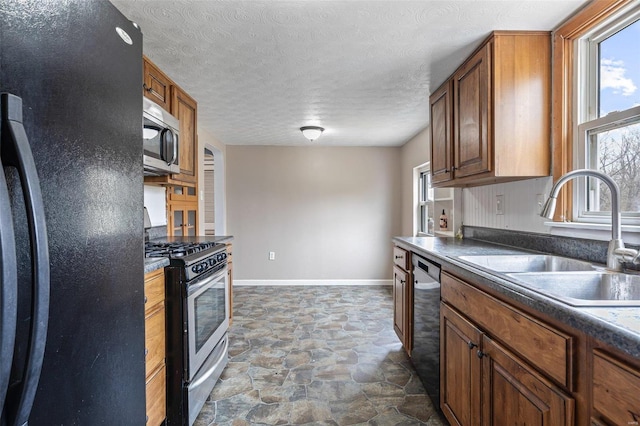 kitchen with dark countertops, a healthy amount of sunlight, appliances with stainless steel finishes, and a sink