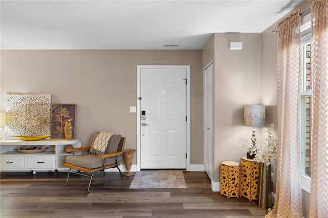 foyer entrance featuring visible vents, baseboards, and wood finished floors