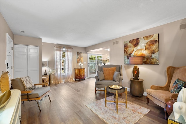 living room with wood finished floors, visible vents, and baseboards