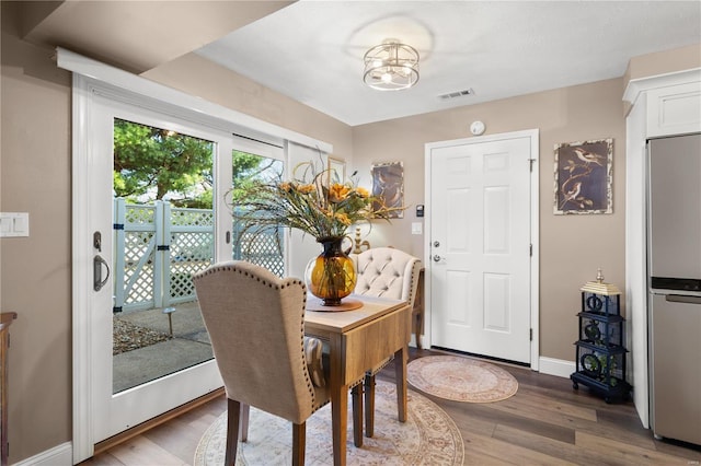 dining area with an inviting chandelier, wood finished floors, visible vents, and baseboards