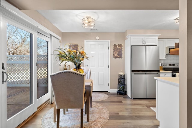 dining area featuring visible vents and light wood-type flooring