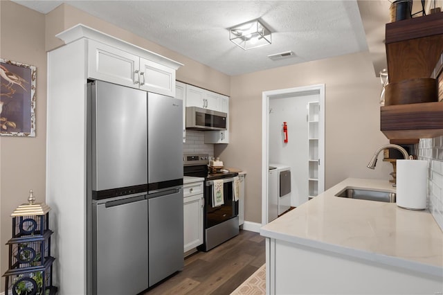 kitchen featuring visible vents, dark wood-style flooring, a sink, decorative backsplash, and appliances with stainless steel finishes