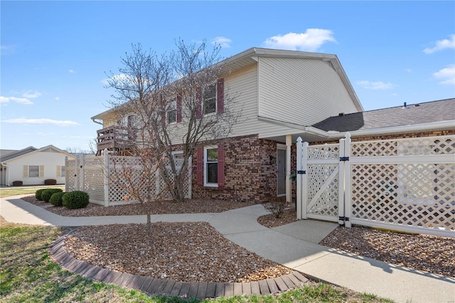 view of property exterior with fence, brick siding, and a gate