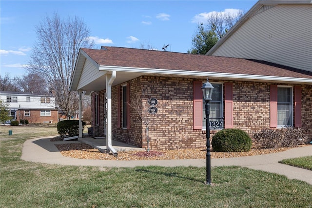 view of home's exterior with a yard, brick siding, and a shingled roof