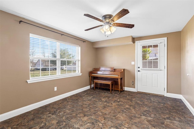 interior space featuring a ceiling fan, stone finish flooring, and baseboards